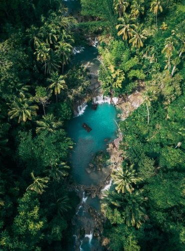 The beautiful waterfall streaming into the river surrounded by greens